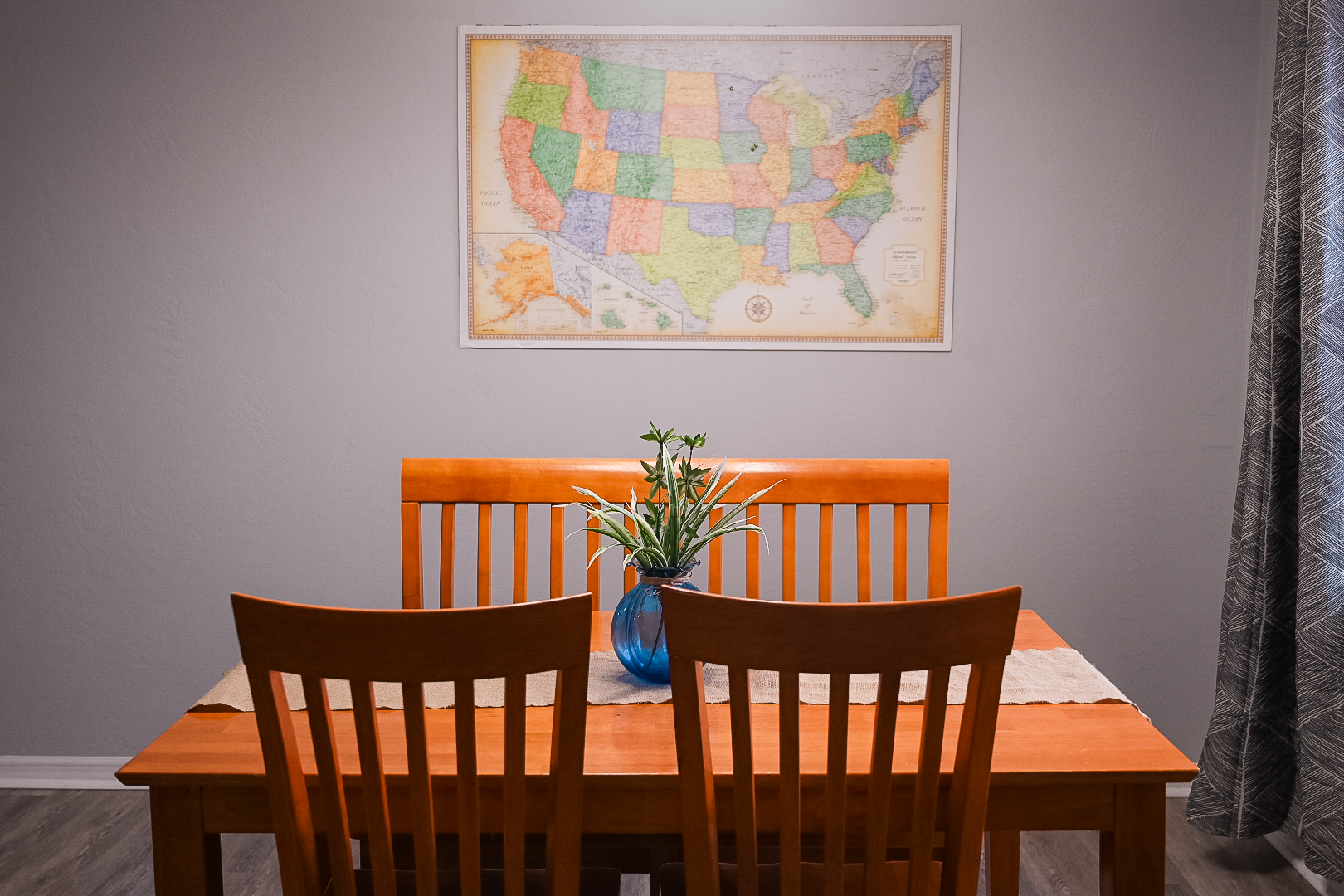 Interior dining area with grey painted walls, a wood table and a map print